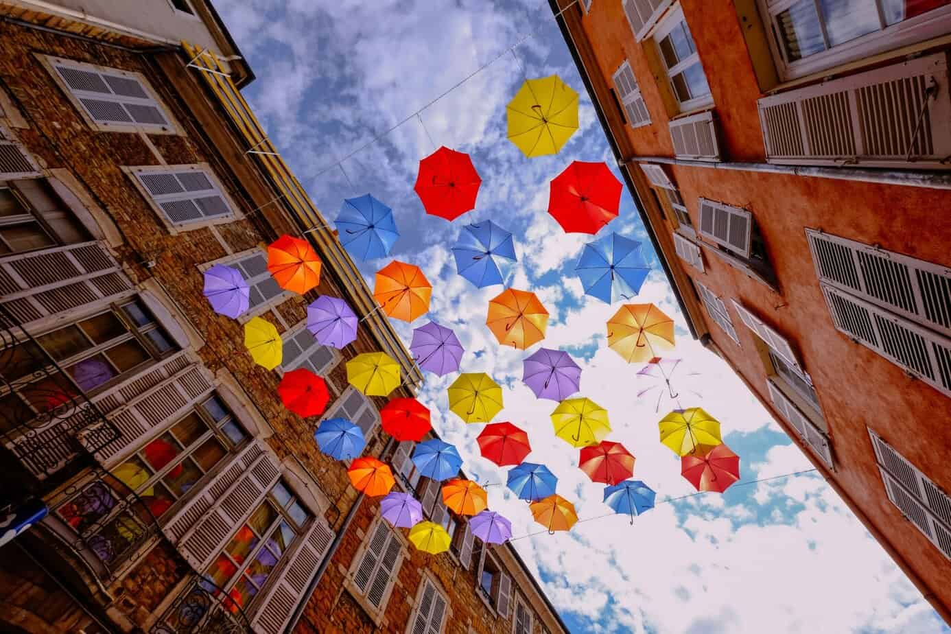 Looking up between two brick buildings at a art installation of colorful umbrellas